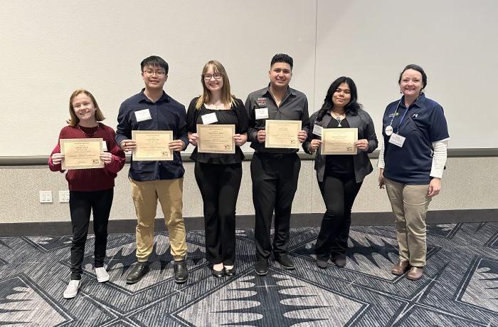 A professor and five students pose with certificates.